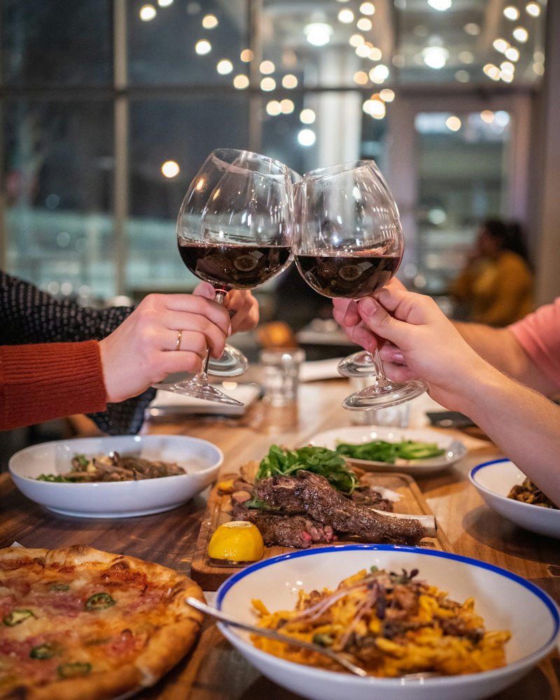 Brinde com taças de vinho sobre uma mesa com pizza e massa